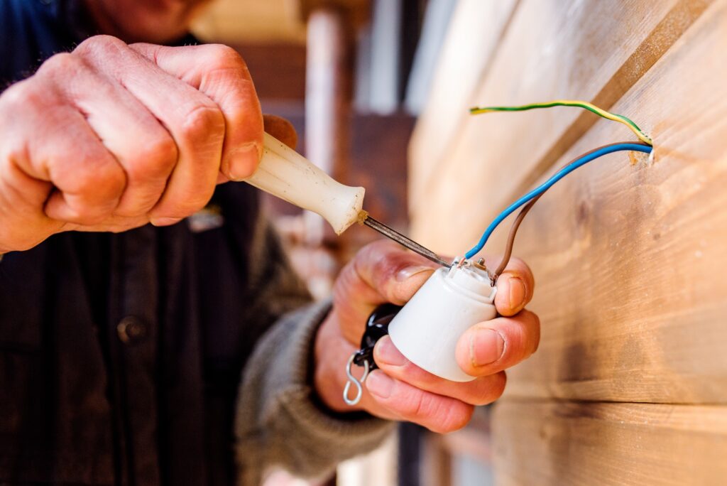 Hands of unrecognizable electrician working with screwdriver